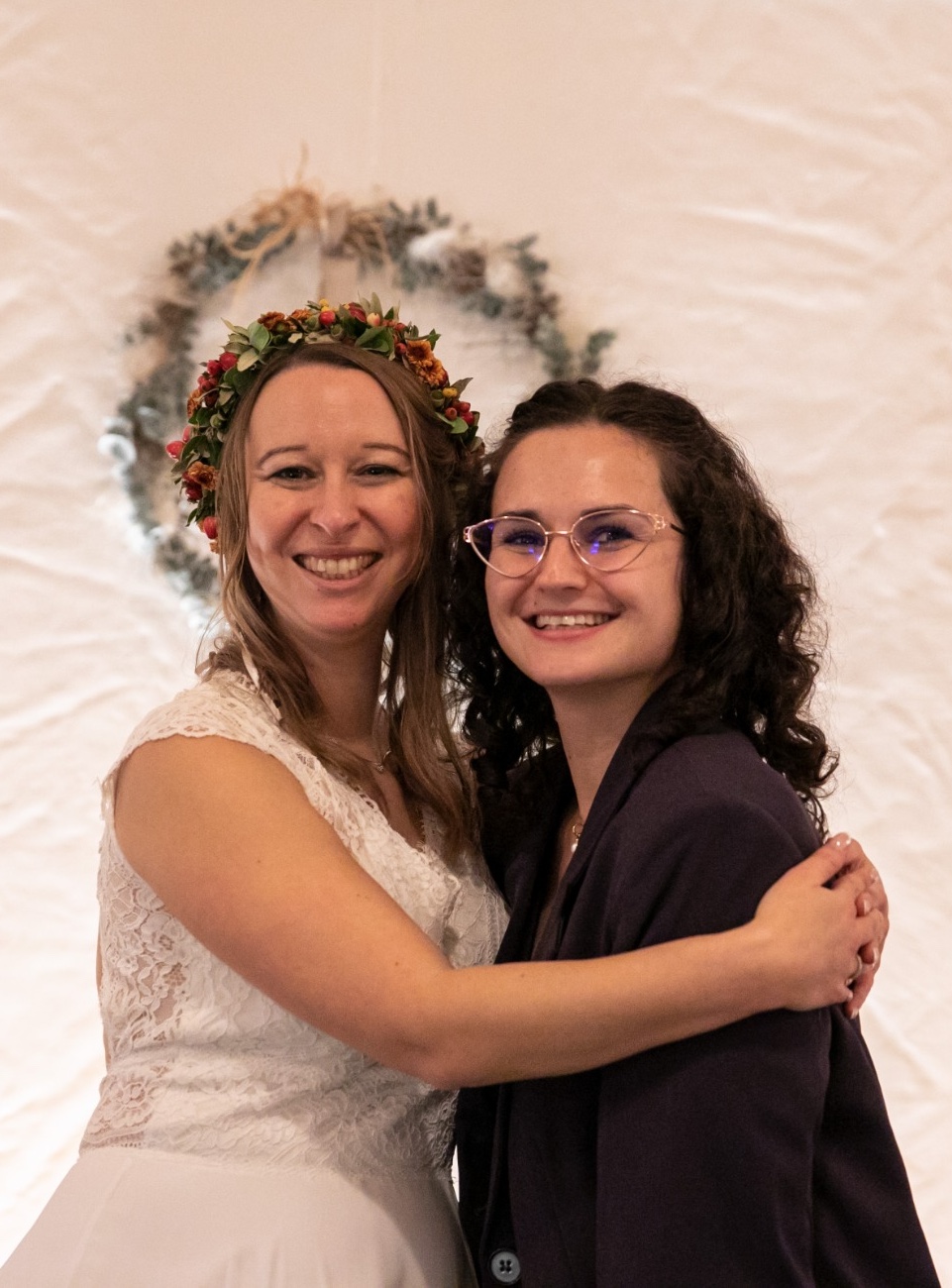 Belinda von BÉLIE Weddings umarmt eine strahlende Hochzeitsperson in Brautkleid und Blumenkranz – Moment nach einer erfolgreichen Hochzeitsplanung in Wien